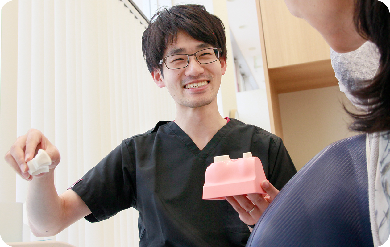 写真：こどもに歯ブラシをすすめる小川院長